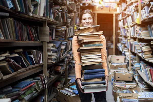 Девушка студент несет большую стопку книг в библиотеке, подготовка к учебе, знания сила, концепция — стоковое фото