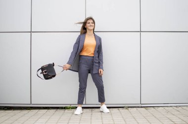 genç kız öğrenci sokakta gri bir duvara karşı duruyor, kentsel bir arka plan karşı şık bir kadın portresi