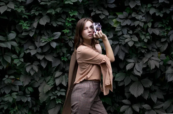 Junge Fotografin steht mit Filmkamera in der Nähe einer Laubwand im Wald, eine Frau fotografiert in der Natur — Stockfoto