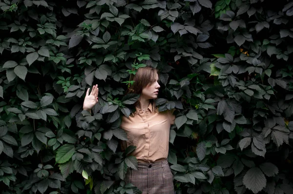 Młoda dziewczyna stoi w zielonych liści sam z naturą, Kobieta dotyka rośliny i marzenia, pojęcie człowieka w przyrodzie — Zdjęcie stockowe