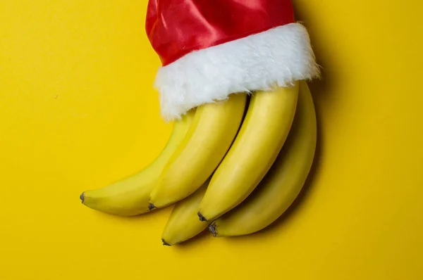 Bananes de Noël sur fond jaune santa claus cap, concept de produits de vacances — Photo