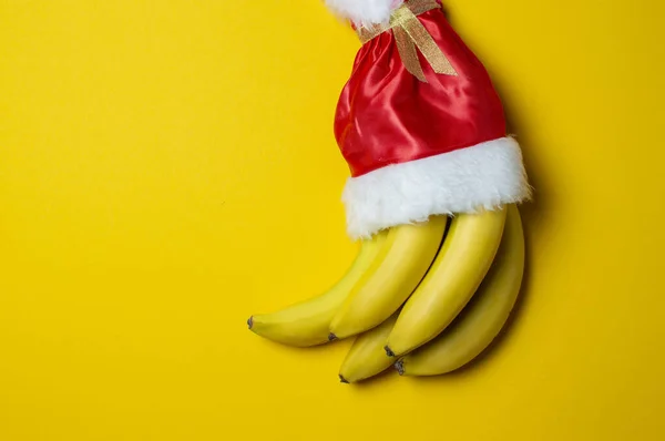 Bananes de Noël sur fond jaune santa claus cap, concept de produits de vacances — Photo