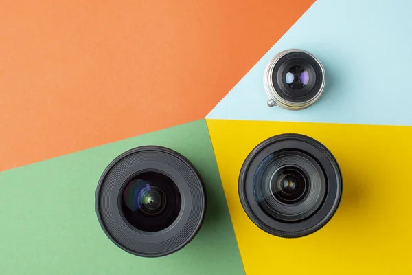 Três lentes fotográficas, sobre um fundo colorido, um conjunto de dispositivos fotográficos para a câmara — Fotografia de Stock