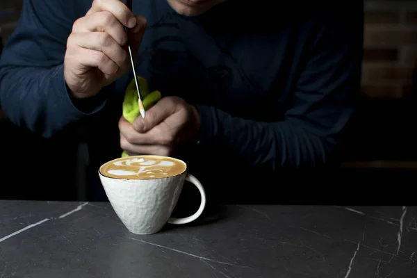 Barista fait du latte art dans un café le matin, un homme dessine une fleur sur du café, gros plan — Photo