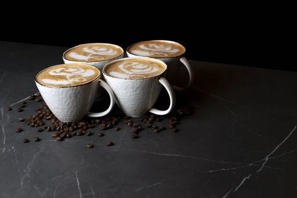 Xícaras de café em uma mesa de mármore em uma cafeteria, arte latte no café com grãos de café — Fotografia de Stock