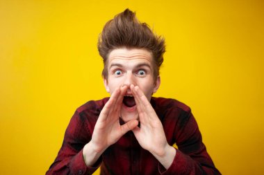 Sarı izole bir arka planda bağıran genç şokta, komik saç stili olan hipster panikliyor, yakın plan