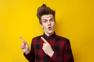 Genç şokta olan adam, sarı izole edilmiş arka plana şaşırır. Mayın alanında komik saç stili şovları olan hippi.