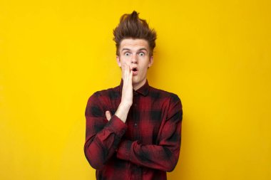 Sarı izole edilmiş bir arka planda komik saç stili olan genç, şoke olmuş, güçlü saç stili olan bir adam.