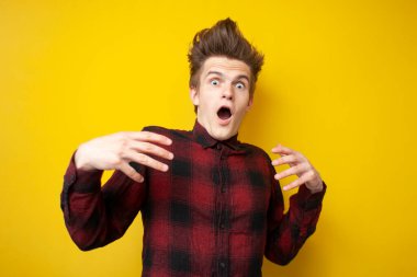 Korkmuş genç adam şaşırdı ve sarı izole edilmiş arka planda bağırdı. Stresli adam şok oldu.