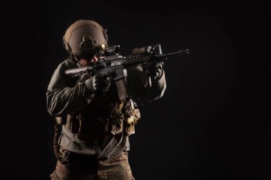 Amerikan modern özel kuvvetleri karanlık bir geçmişe karşı, askeri teçhizat içinde bir asker silah tutuyor ve nişan alıyor, seçkin birlikler