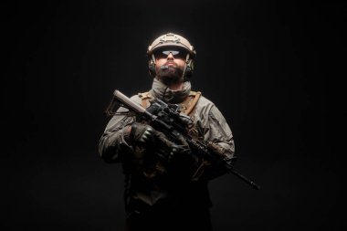 Amerikan modern özel kuvvetleri karanlık bir geçmişe karşı, askeri teçhizatlı bir asker silah tutuyor ve yukarı bakıyor, seçkin birlikler, deniz piyadesi savaşa hazır.