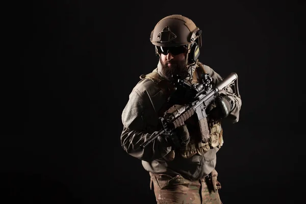 American special forces against a dark background, modern soldier in military equipment holds weapons and looks at the copy space, elite troops