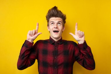 Komik saç stili olan genç adam sarı izole bir arka planda fotokopi odasında beliriyor.