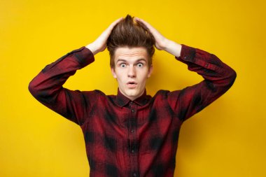 Şok olmuş genç adam saçına dokunuyor ve sarı izole edilmiş arka planda merak ediyor. Kuaförlü hippi öğrenci saçını kestiriyor.