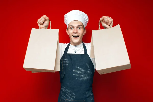 Young Cook Holds Grocery Bags Red Background Guy Chef Uniform — Stock Photo, Image