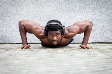 Afro-Amerikan atletizm sporcusu, duvarların arkasında antrenman yapıyor, atletik vücutlu adam ısınıyor, sağlıklı yaşam tarzı kavramı geliştiriyor.