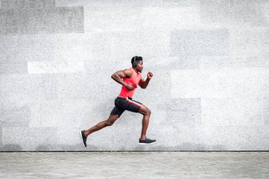 Afro-Amerikalı koşucu şehrin arka planına doğru hızla koşuyor, sporcu treni yolda, genel plan...