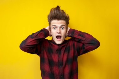 Sarı izole bir arka planda bağıran genç şokta, komik saç stili olan hipster panikliyor, yakın plan