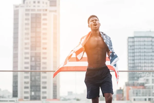 black lives matter concept, african american guy with usa flag shouting against city in protest, aggressive rebellion activist