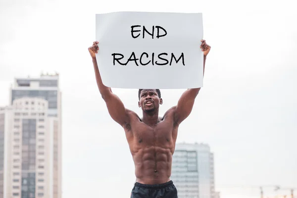 アフリカ系アメリカ人の男性がポスターを持って抗議して叫び人種差別の概念に終わる — ストック写真