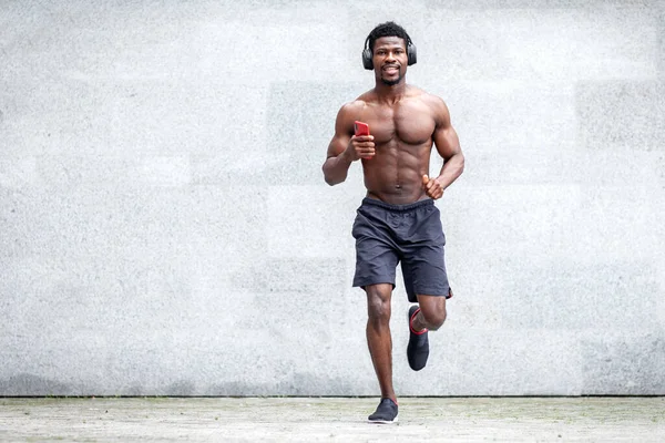 Afro-Amerikalı koşucu şehrin arka planında hızla ileri doğru koşuyor, sporcu adam sokakta eğitim görüyor ve müzik dinliyor.