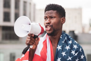 Amerika bayraklı Afrikalı Amerikalı adam megafonla, Amerikan vatanseveri ve aktivist protestocuyla konuşuyor. Siyahların hayatı meta kavramı.