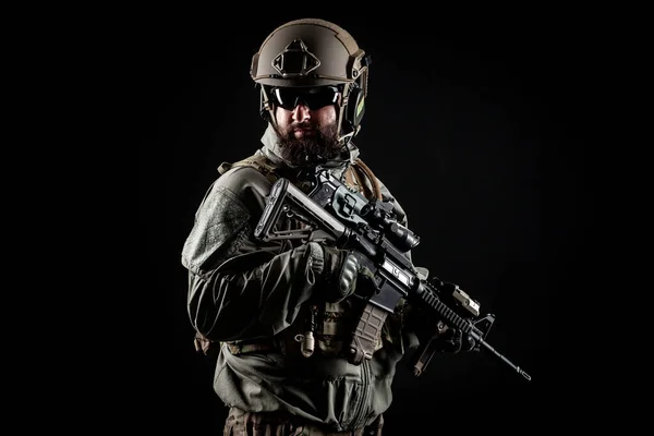 American commando in a military uniform with a weapon looks at copy space, a marine on a black background, a member of the elite troops, war concept