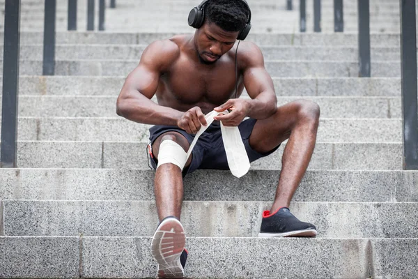 Conceito Lesão Joelho Cara Afro Americano Enfaixando Perna Com Uma — Fotografia de Stock