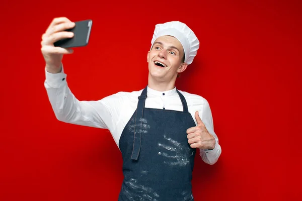 Jovem Chef Uniforme Detém Smartphone Tira Uma Selfie Fundo Vermelho — Fotografia de Stock