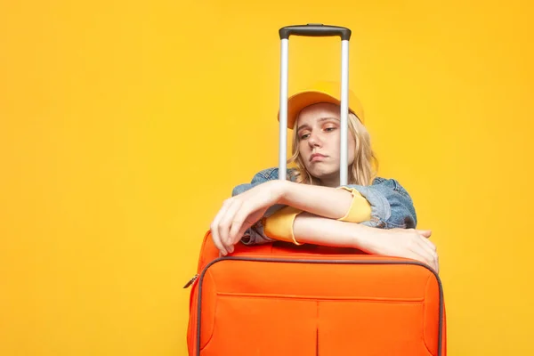 closed borders concept. unhappy girl tourist with luggage sad on a yellow isolated background, woman dreams of traveling, travel ban