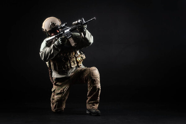 American special forces, a soldier in a military uniform with a weapon attacks on a black background, a ranger for special operations, copy space