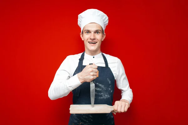 Louco Jovem Chef Uniforme Detém Faca Placa Vermelho Isolado Fundo — Fotografia de Stock