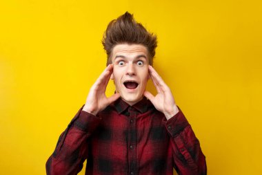 Sarı izole bir arka planda bağıran genç şokta, komik saç stili olan hipster panikliyor, yakın plan