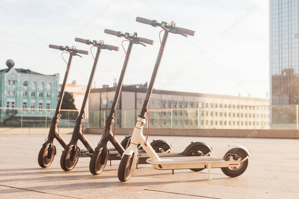electric scooters stand on the street against the background of the city, transport of the future, eco transport rental