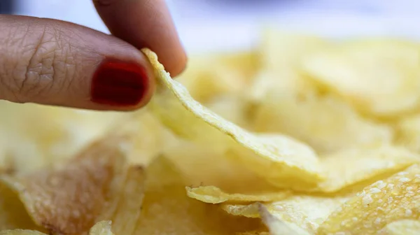 Lezzetli patates cipsi yiyen kadın parmaklarına yakın çekim - yüzeysel alan derinliği