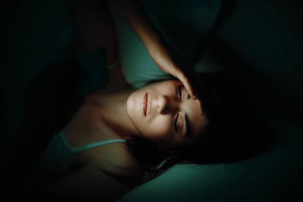 頭痛とベッドでのスマート フォンの女性 — ストック写真