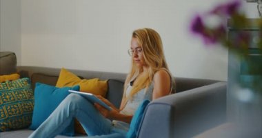 Tablet Pc kullanarak Güzel kız yüksek kaliteli 4k 12bit görüntüleri evde kanepede oturan. Kadın sörf web, sosyal ağlar, online alışveriş bir şey arıyor. Sinematik görünüm