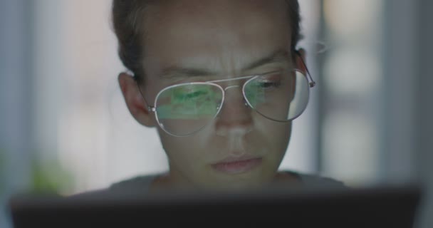 Imágenes de alta calidad de 4k 12bit. Joven oficinista con gafas tipeando en un portátil, resolviendo problemas. Trabajo nocturno. Mujer en el ordenador está buscando una solución al problema . — Vídeos de Stock