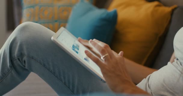 Hochwertige 4k 12bit Filmmaterial von schönen Mädchen mit Tablet-PC sitzt auf der Couch zu Hause. Frau surft im Internet, soziale Netzwerke, sucht etwas im Online-Shop. Filmischer Look — Stockvideo