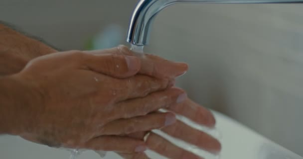 Imágenes de alta calidad de 4k 12bit. Cuidado corporal. Persona lavando las manos en el baño de diseño moderno en casa. Hombre lavando la mano masculina con jabón y agua bajo el grifo en el baño moderno — Vídeo de stock