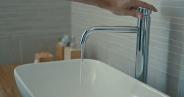Yüksek kaliteli 4k 12bit görüntüleri. Vücut bakımı. Evde modern tasarım banyoda ellerini durulama kişi. Erkek modern banyoda musluk altında sabun ve su ile erkek el yıkama