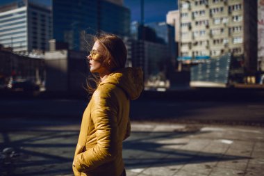 Seyahat, uzun sarı saçlı, şehir merkezi sokak, sokak aşağı çekim yürüyüş bir sarı ceket, sarı güneş gözlüğü takmış Genç Avrupalı bir bayan. Hatta ışık.