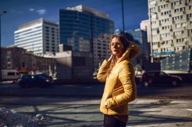 Seyahat, uzun sarı saçlı, şehir merkezi sokak, sokak aşağı çekim yürüyüş bir sarı ceket, sarı güneş gözlüğü takmış Genç Avrupalı bir bayan. Hatta ışık.