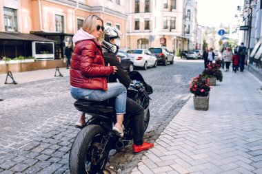 Güzel kadınlar! Sokağın bir modern siyah building yakınındaki bir motosiklet kask ile siyah bir motosiklet üzerinde oturan genç güzel seksi esmer. Tarafına bak.