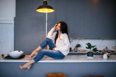 Güzel kız beyaz bir ceket ve kot pantolon kanepeye evde dinleniyor. portre, İskandinav tarzı