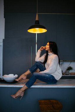 Güzel kız beyaz bir ceket ve kot pantolon kanepeye evde dinleniyor. portre, İskandinav tarzı