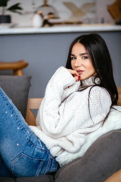 白いジャケットとジーンズで美しい少女は自宅のソファで休んでいます 北欧スタイルの肖像画 — ストック写真