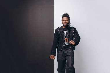 Bir çekici gülümseyen siyah adam siyah ceket ve gri arka plan üzerinde siyah pantolon