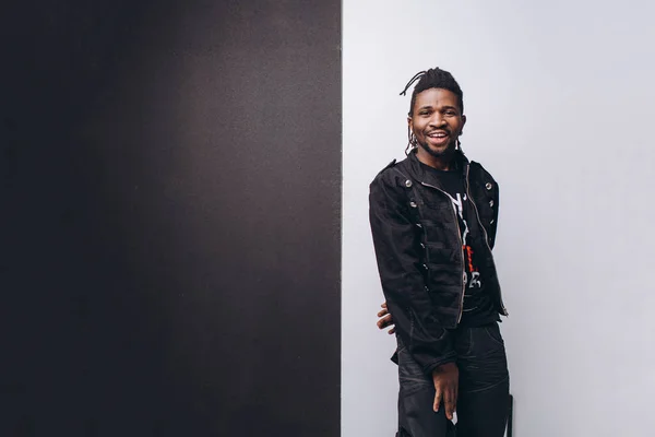One attractive smiling black man in black jacket and black pants over gray background