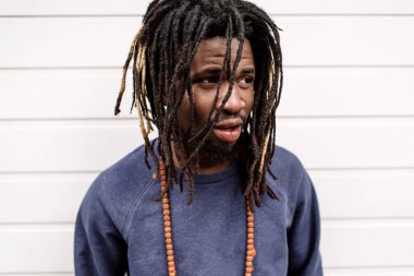 Güzel Afrikalı-Amerikalı dreadlocks, at kuyruklu saç kahverengi pantolon ve evler, arka planı Mavi kazak ile şehir